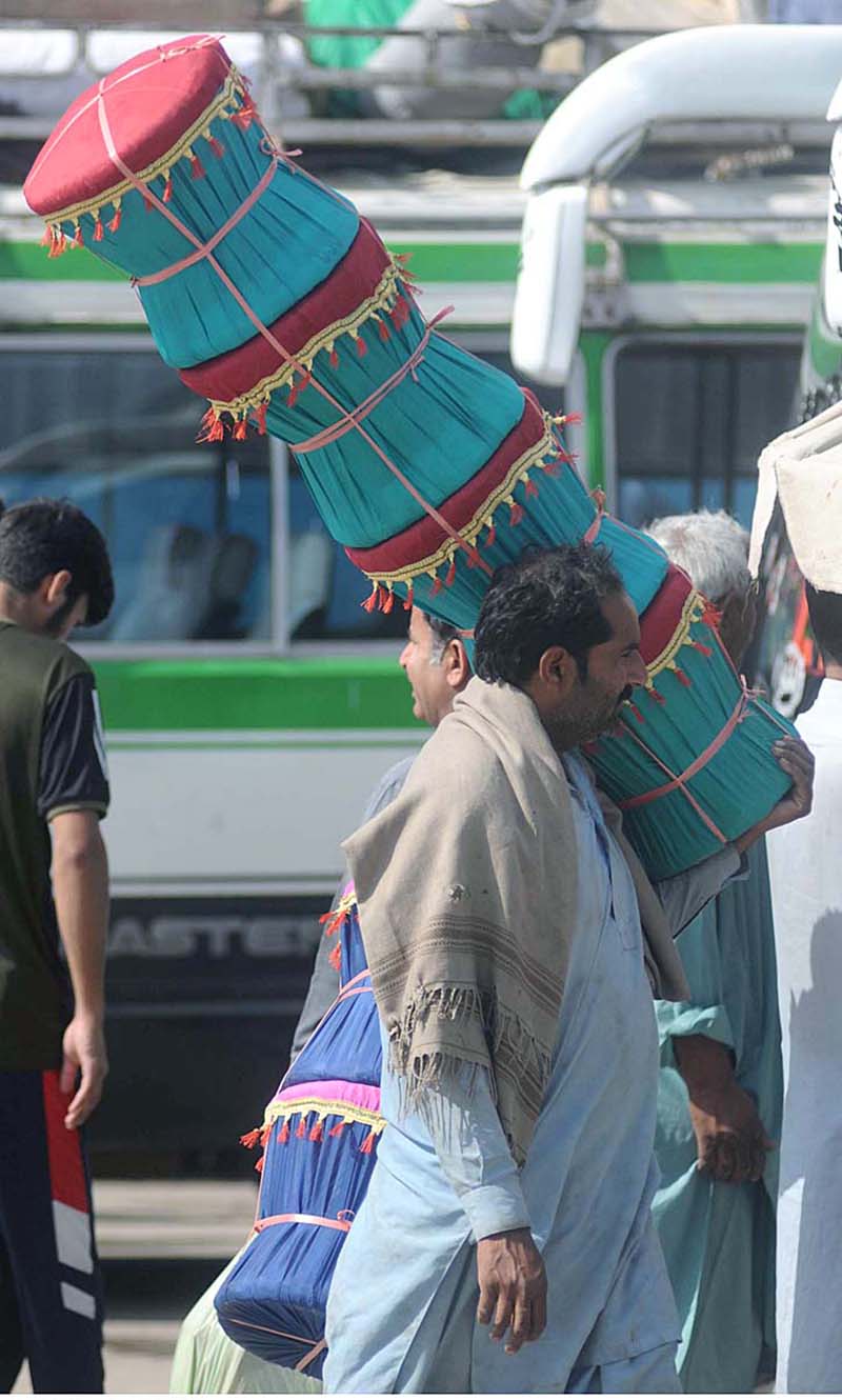 A street vendor is roaming and selling traditional chairs (Mora) at Pir Wadai