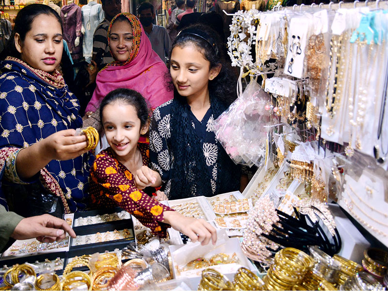 Woman with her girls purchasing jewelry during Eid shopping in preparation of upcoming Eid-ul-Fitar at cloth market Latifabad