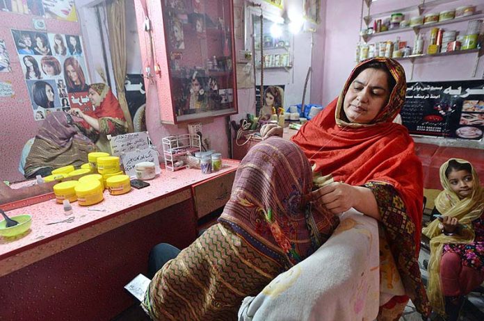 A beautician uses a threading technique to remove hair from a customer during preparation for the upcoming Eid-ul-Fitr celebrations