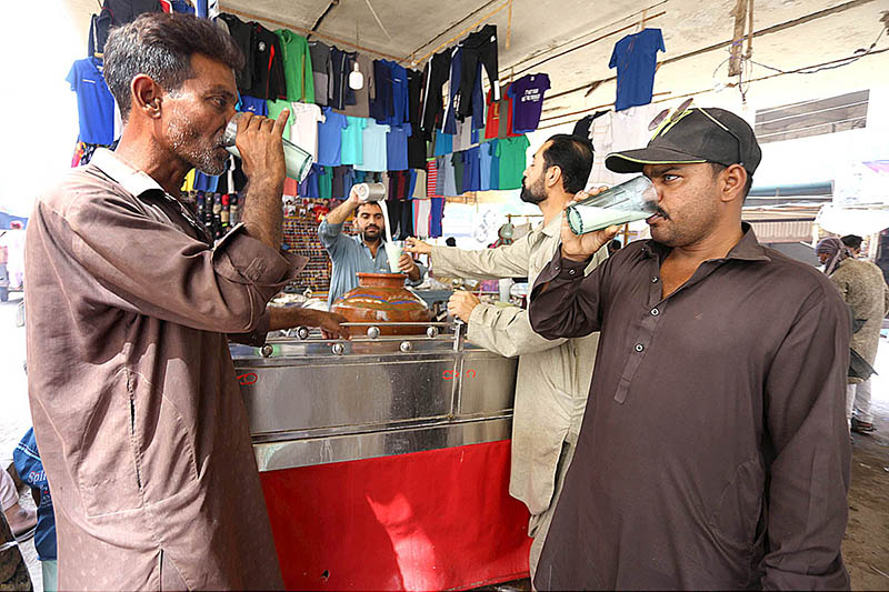On a hot day in the city, people are seen quenching their thirst with (Lassi) purchased from a roadside vendor located at Bacha Khan Chowk
