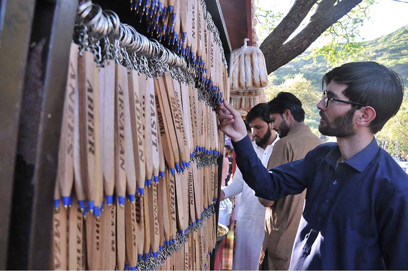 A visitor selects key chain from a vendors stall at the picnic point Daman e Koh, celebrating the 2nd day of Eid ul Fitr