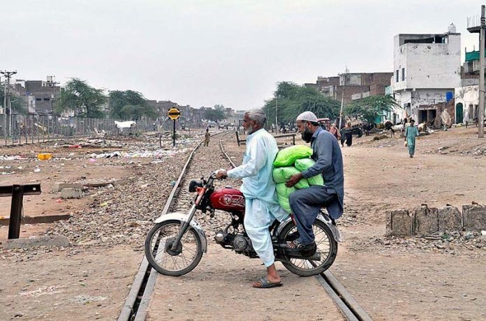 Motorcyclists crossing rail tracks while carrying free Atta