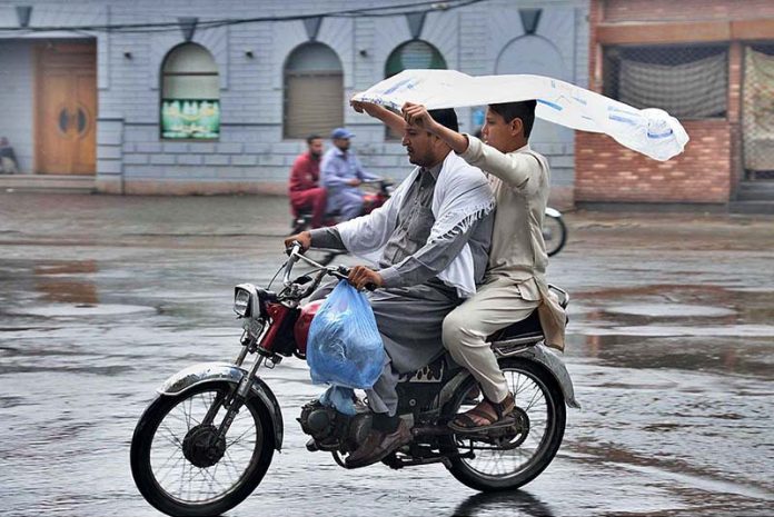 Commuters on his bike moving towards his destination during rain in the Provincial Capital