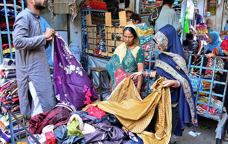 A vendor displaying ladies clothes to attract the customer at Cloth Market.