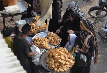 Women busy in purchasing traditional food items Samosas from a vendor at Faqir Ka Pir Bazaar