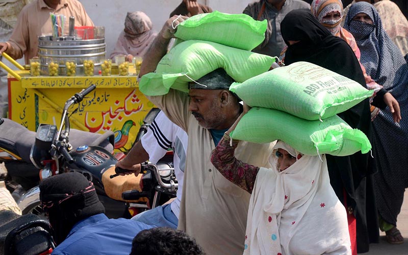 People carrying flour bags on their heads back home after taking free flour bags from the Government.