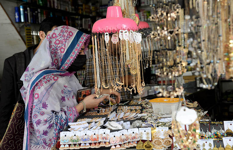 A girl selects for purchasing matching jewelry with her dress during Eid shopping in preparation of upcoming Eid-ul-Fitar at Bano bazaar.