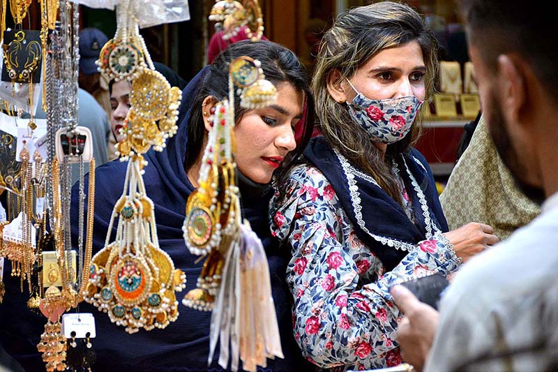 Girls selecting and purchasing jewelry during shopping in preparation of upcoming Eid-ul-Fitar at Resham bazaar