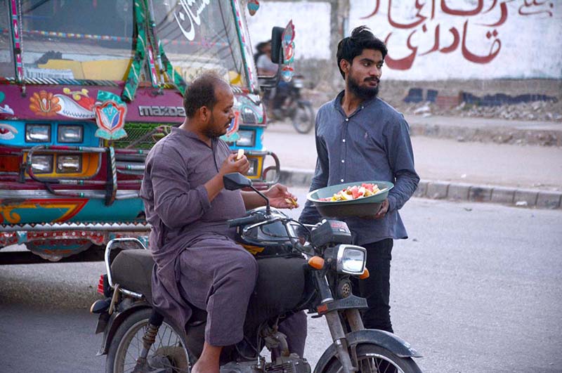 A volunteer giving fruit to a motorcyclist to break the fast during holy month of Ramadan