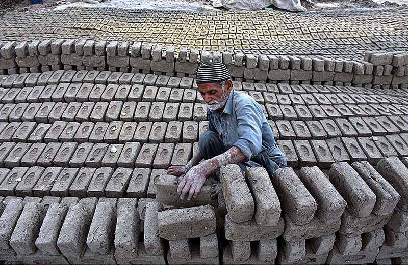 An elderly labourer busy in arranging raw bricks at a kiln as the world marks International Labour Day. May 1st, International Workers' Day, commemorates the historic struggle of working people throughout the world. In 1884, the Federation of Organized Trades and Labour Unions passed a resolution stating that eight hours would constitute a legal day's work from and after May 1, 1886
