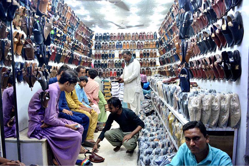 Youngsters are selecting and purchasing sandals during shopping in preparation of upcoming Eid-ul-Fitar at Naya pul road