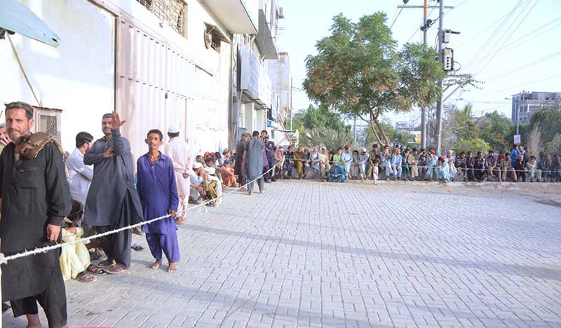 A large number of people standing in a queue to get registered for iftari in a factory at Korangi Industrial
