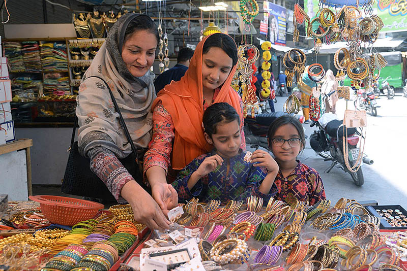 A woman is shopping for jewelry with her daughters in preparation for the upcoming Eid-ul-Fitr at Anarkali Bazar