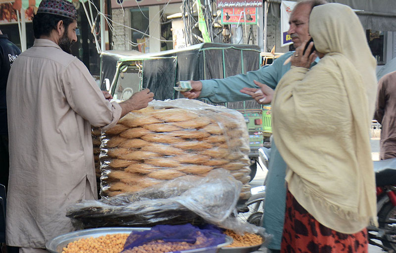 A shopkeeper is selling traditional food item (Pheeni) near iftar time at his shop