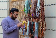 Customer is buying colorful tasbihs from a roadside vendor during the last days of Ramadan