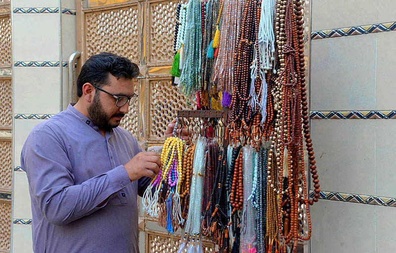 Customer is buying colorful tasbihs from a roadside vendor during the last days of Ramadan