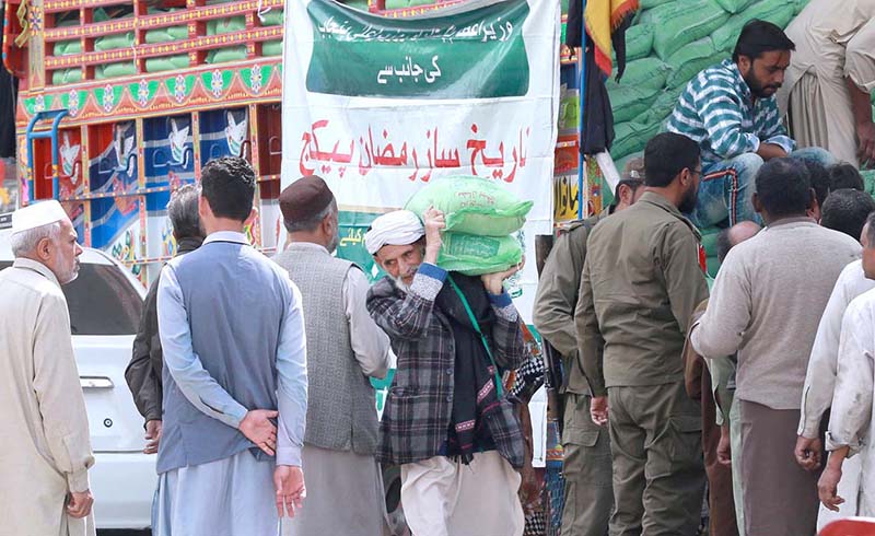 People on the way carrying free bags of flour after receiving from a distribution center at Dhoke Khabba