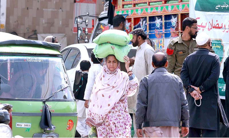 People on the way carrying free bags of flour after receiving from a distribution center at Dhoke Khabba