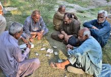 Elderly men playing cards to pass their time while sitting along roadside at Canal road in Provincial Capital City