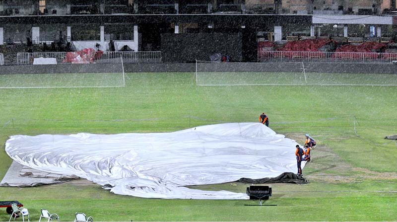 PCB workers busy in covering the pitch with plastic sheets during rain at Pindi Cricket Stadium