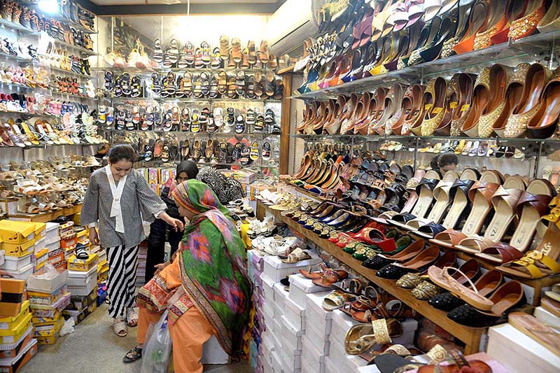 Customers selecting and purchasing shoes from a shopkeeper during preparation of upcoming Eid-ul-Fitr.