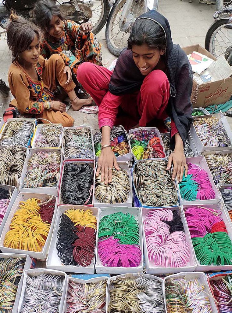 A young female vendor displaying colorful bangles to attract the customers at Resham Gali in connection with upcoming Eid-ul-Fitar