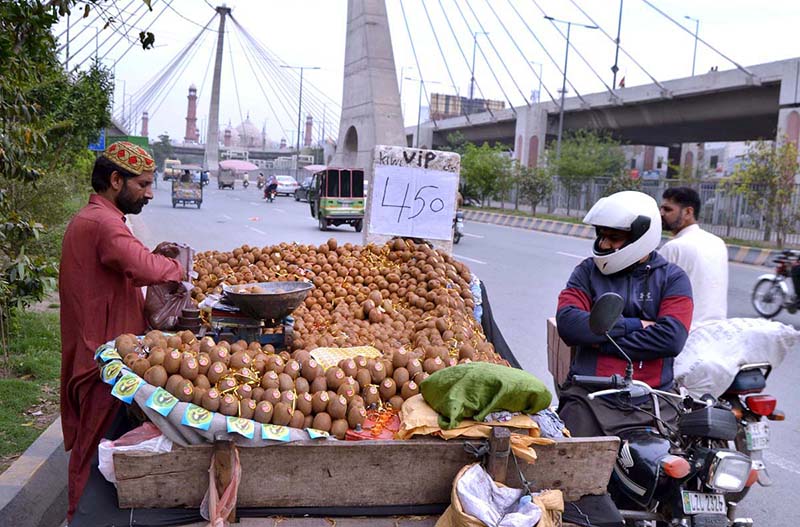 A customer is buying kiwi from a roadside vendor at Ravi Road