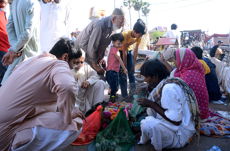 People purchasing different birds from a vendor at the bird market in the Saddar area