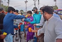 A young volunteer distributing sweet drink to people at the time of Iftar along the roadside