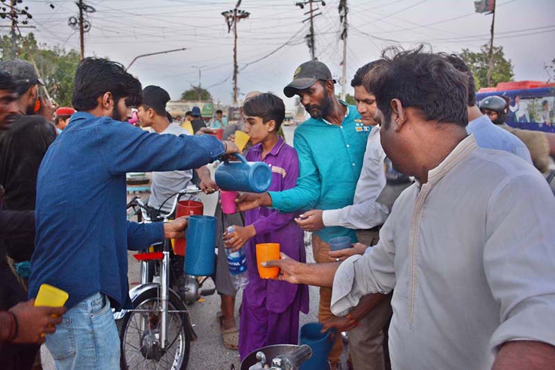 A young volunteer distributing sweet drink to people at the time of Iftar along the roadside