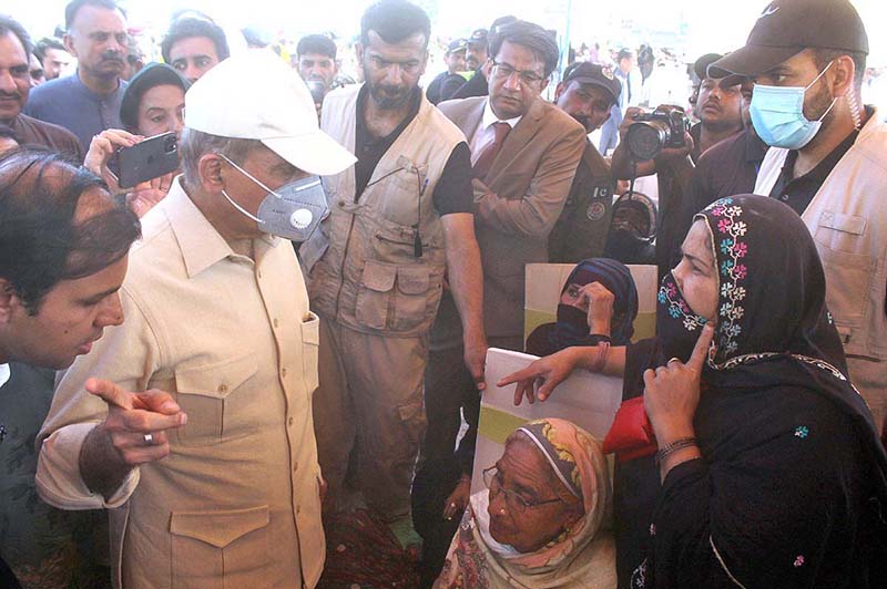 Prime Minister Muhammed Shehbaz Sharif talking with the woman during his visit at free flour distribution center