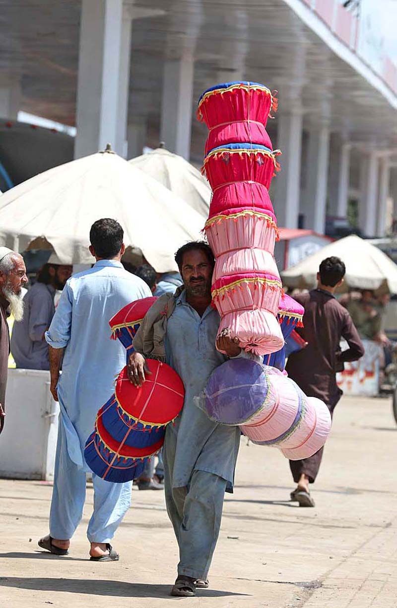 A street vendor is carrying handmade bamboo cane sitting stool by on his shoulders for selling while shuttling in streets to earn livelihood in twin cities