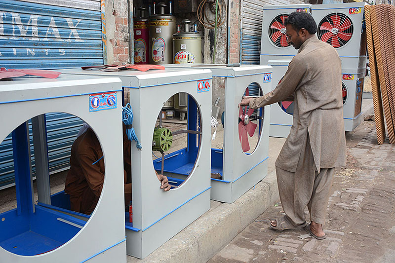 A worker is preparing room coolers at his workplace due to its increasing demand during summer season