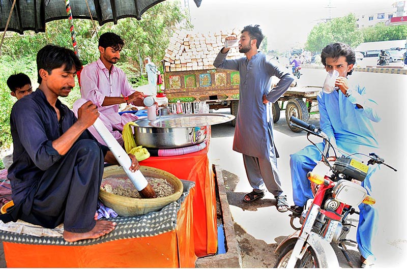 People drinking traditional drink thadal from a vendor during hot weather