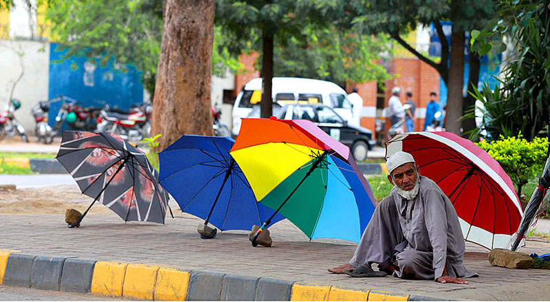 A street vendor displaying umbrellas on the roadside to attract customers at Jinnah Super Market