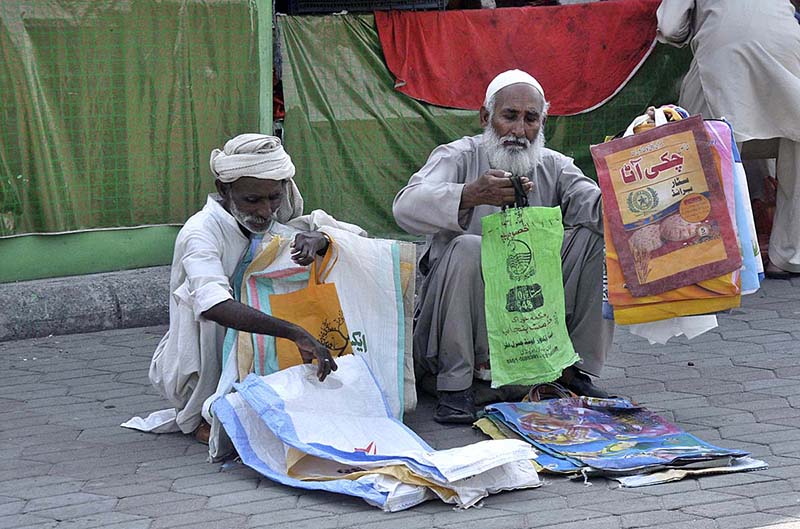 Two elderly vendors waiting for customers to sell shopping bags at Sunday Bazaar