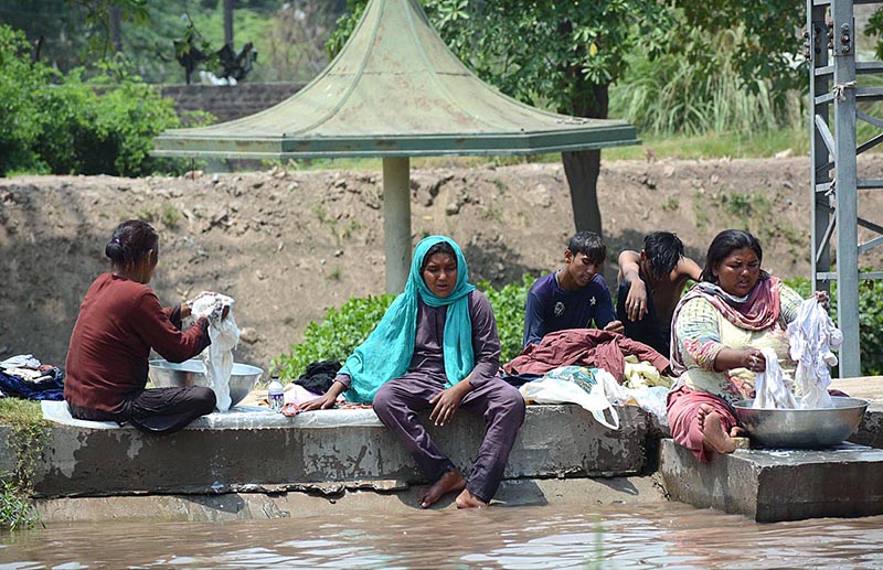 Gypsy women washing clothes at the bank of a canal