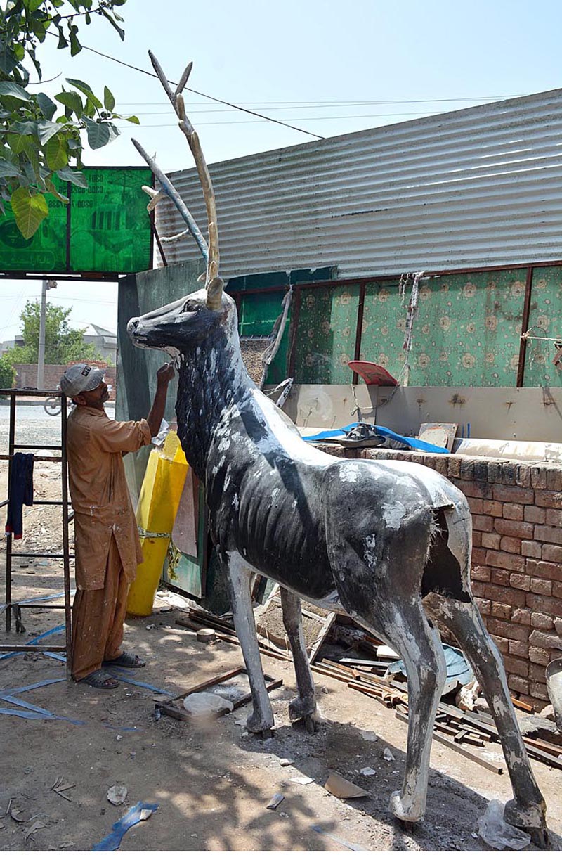 Mason is preparing statue of a deer at his work place