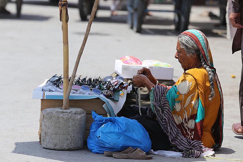 A female vendor displaying sunglasses to attract customers at her setup at Khanna Pul