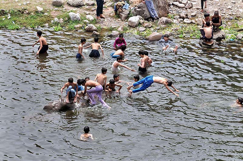 Youngsters jumping and bathing in water channel of Rawal Dam in Federal Capital to get some relief from hot weather in Federal Capital