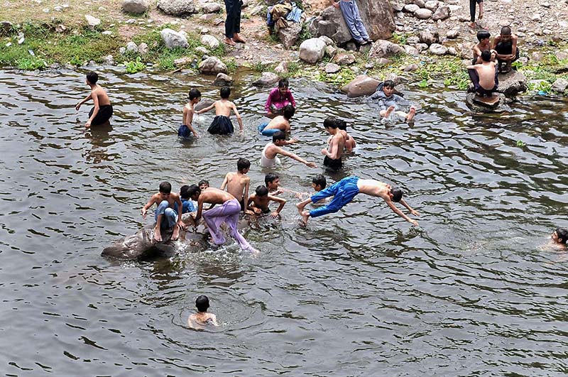 Youngsters jumping and bathing in water channel of Rawal Dam in Federal Capital to get some relief from hot weather in Federal Capital