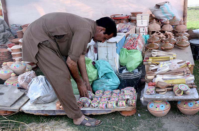 Vendor busy in arranging and displaying clay made pots to attract the customer at his roadside setup