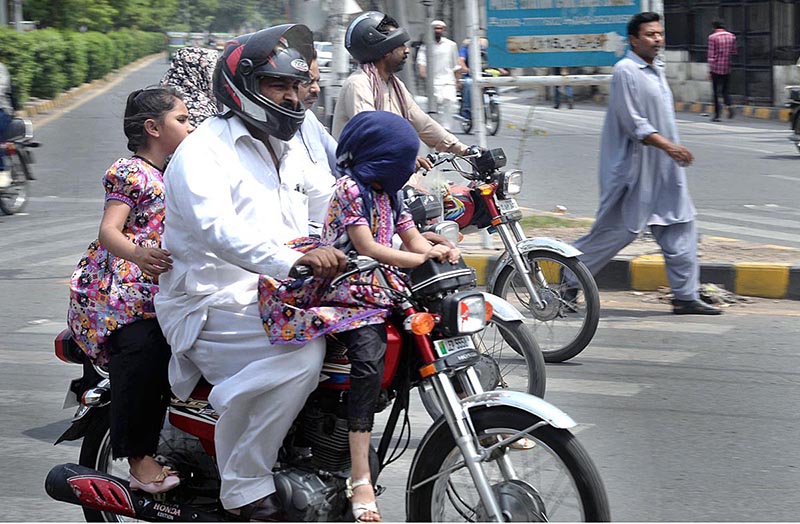 A child on a motorcycle covered herself with a handkerchief to avoid the heat and the strong sun