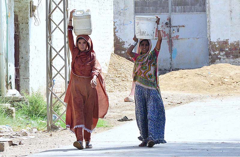 Women carrying pots on her head after filling clean water at Latifabad