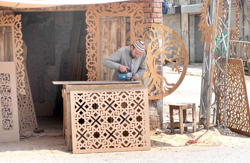 A carpenter busy in carving designs on a wooden sheet at his workplace