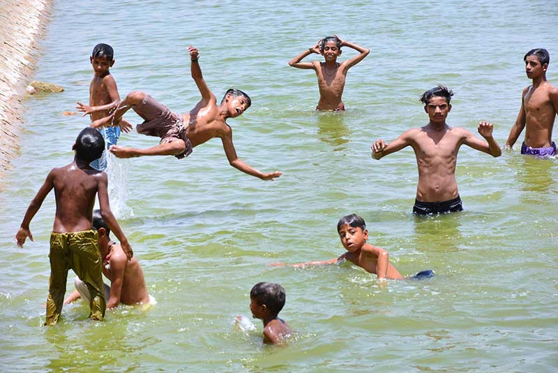 Youngster diving to swim in the water pond to get some relief from hot weather in the city at railway station area