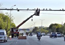 A worker busy in the repairing CCTV cameras during maintenance work at Srinagar Highway in Federal Capital
