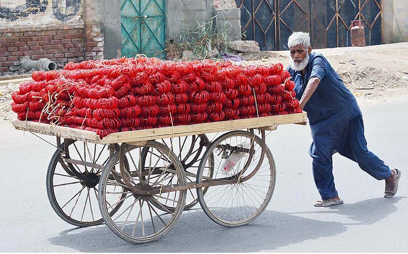 An elderly vendor pushing hand cart loaded with bangles at Latifabad