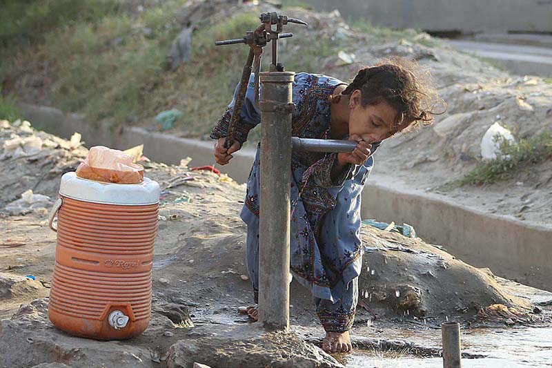 A girls drinking water from hand pump at Hala Naka Area