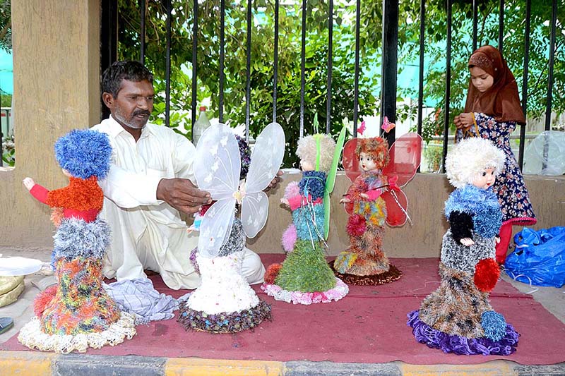 A vendor preparing plastic dolls to attract customers at his roadside